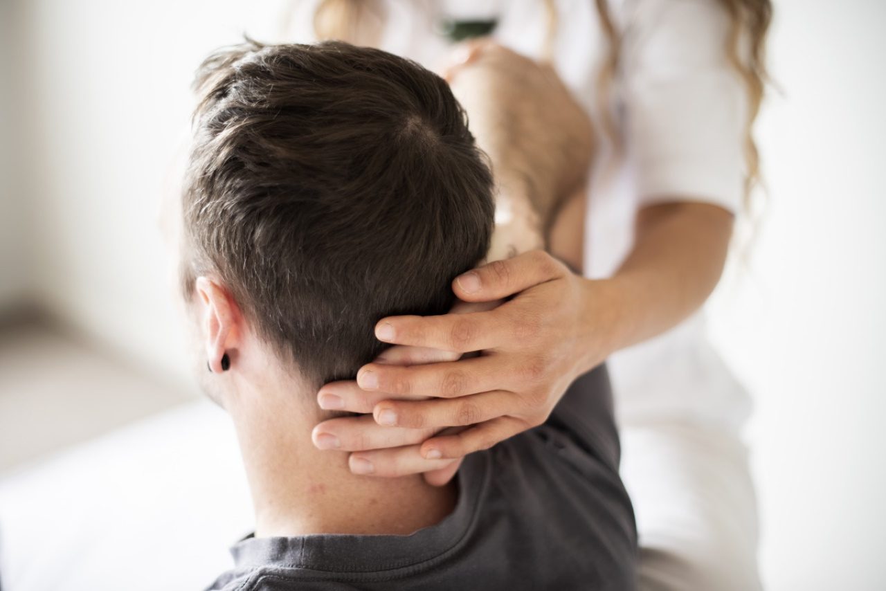 Person receiving shiatsu massage therapy, with therapist applying pressure to back with hands